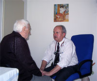 Pacient s doktorem při osobním rozhovoru, oba sedí proti sobě a povídají si